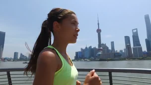 Asian woman running in city of Shanghai, China on famous boardwalk with skyline — Stock Video