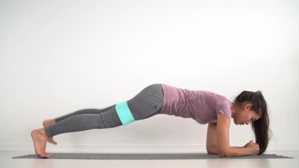 Dirençli bantlı fitness kızı bacak kaldırma egzersizi yapıyor. — Stok video