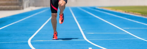 Atleta sprinter runner entrenamiento sprinting carrera dinámica en pistas de atletismo en el estadio. Banner panorámico de hombre piernas y zapatillas de correr —  Fotos de Stock