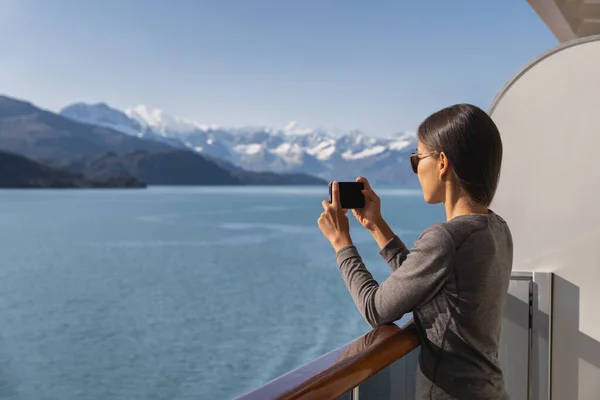 Pasajero de un crucero de Alaska fotografiando un paisaje increíble entrando al Parque Nacional Glacier Bay, Estados Unidos. Turista mujer tomando foto utilizando el teléfono inteligente celular móvil en vacaciones de viaje —  Fotos de Stock