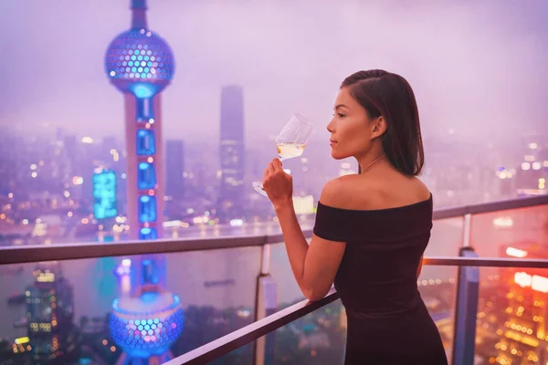 高級上海ライフスタイル中国旅行で白ワインを飲むアジアの女性。街のテラスビューで黒のドレスでエレガントなモデル,ハイエンドの生活 — ストック写真
