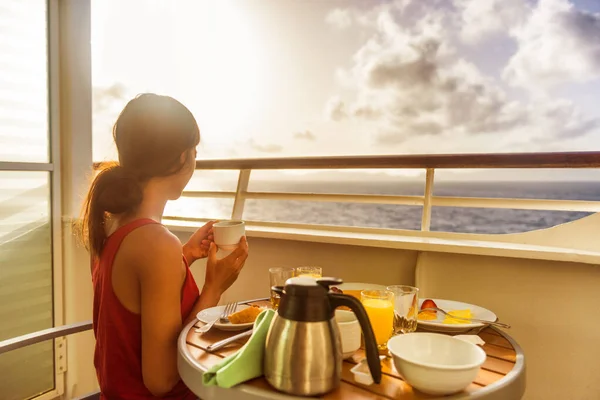 На круизном лайнере женщина-путешественница завтракает в номере на балконе люкса, наслаждаясь утренним видом на Карибский океан. Летние каникулы люди пьют кофе — стоковое фото
