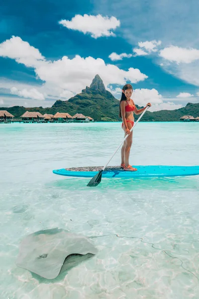 SUP Stand-up paddle board woman wwimming with stingrays tourist tour activity happy Asian woman on Bora Bora island beach at Tahiti overwater bungalow hotel, férias de viagem — Fotografia de Stock