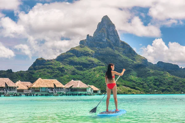 Tahiti Bora Bora adası tatil aktivitesi su sporu yapan kadın Fransız Polinezyası 'ndaki lüks tatil otelinde ayakta yüzme tahtasında sörf yapıyor. Otemanu Dağı yaz tatili manzarası — Stok fotoğraf