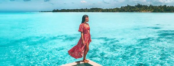 Cestovní dovolená. Elegantní asijská žena relaxující v luxusním bazénu resort s výhledem na tyrkysový oceán v červené pláži pokrytí maxi šaty. Letní sluneční bikiny životní styl. Panoramatický prapor krajiny — Stock fotografie