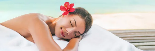 Spa de masaje y cuidado corporal al aire libre en la playa en el complejo de vacaciones de lujo. Mujer belleza asiática relajante durmiendo acostado en la mesa durante el tratamiento de aromaterapia con aceite de coco —  Fotos de Stock