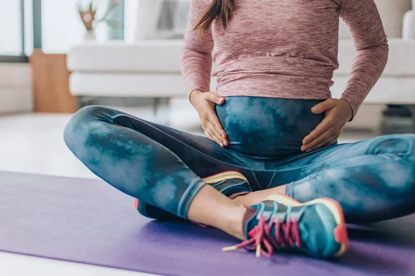 怀孕时穿活动服。孕妇穿着全套瑜伽腿在家里的地席上进行体重训练 — 图库照片