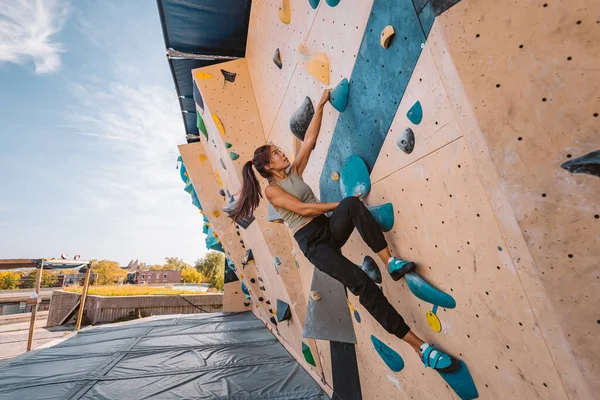 Asiatische Bergsteigerin klettert Boulderwand im Fitnessstudio hinauf. Spaß an sportlicher Betätigung im Freien — Stockfoto