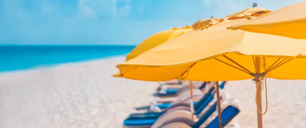 Beach Caribbean vacation travel banner landscape. Yellow umbrellas and sun chair loungers on sand at ocean for summer holidays. Panoramic background — ストック写真