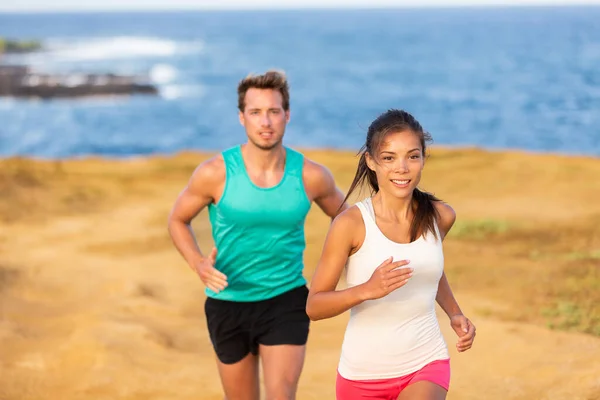 Fit run mensen paar joggen voor fitness hardlopen op het strand landschap natuur buiten. Vrouwen en mannen sporten atleten trainen cross-country trail hardlopen. Team partners, Aziatische vrouw, Kaukasische man Stockafbeelding