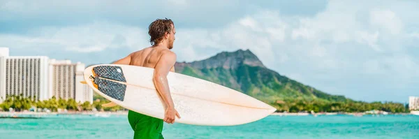 Surfer man going surfing on Waikiki beach in ocean waves carrying surfboard. Summer fun watersport active lifestyle banner panoramic — ストック写真