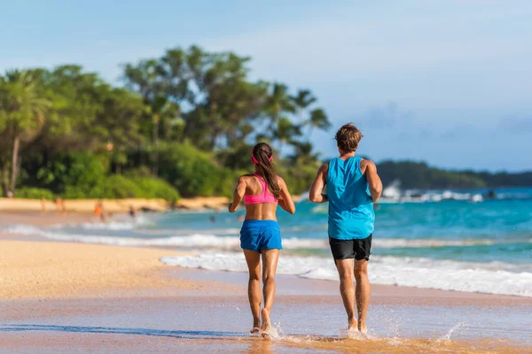 Пара бігунів біжить на пляжі. Відкритий літній тренажерний зал вид ззаду жінки і чоловіка тренування бігу разом — стокове фото