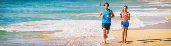 Kumsalda koşan sporcular kardiyo kovan egzersizi yapıyorlar. İki koşucunun panoramik bayrağı mavi okyanuslu kumda çıplak ayakla antrenman yapıyor. — Stok fotoğraf