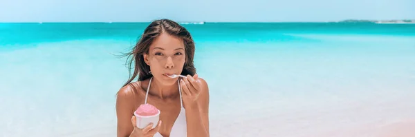 Postre de helado en la playa. Mujer asiática feliz comiendo delicioso yogur de frutas congeladas o batido de Acai bowl comida saludable. Bandera panorámica de fondo azul océano — Foto de Stock