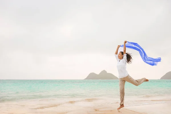 在海滩上自由快乐无忧无虑的亚洲女人在寒假时带着蓝色围巾在风中自由自在地跳跃。妇女的积极态度、身体健康、健康和健康 — 图库照片
