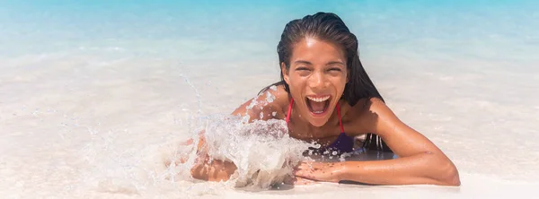 Summer fun happy woman swimming in ocean wave in beach surprised funny from wave splash sunbathing in Caribbean travel vacation. Panoramic banner of holiday — Stock Photo, Image