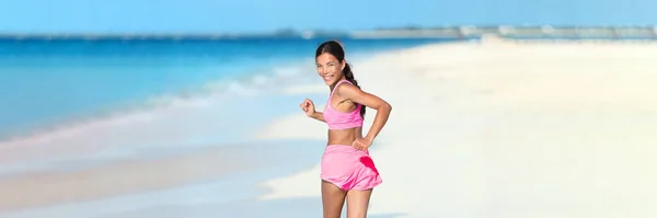 Happy running fitness girl guardando indietro sorridente sulla pista da spiaggia jogging stile di vita sano attivo. Asiatico donna atleta esercitare cardio working out in estate all'aperto Foto Stock Royalty Free