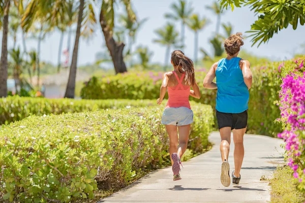 Läuferinnen und Läufer, die von hinten auf dem Seitenstreifen laufen. Im Sommer außerhalb des Cardio-Workouts trainieren zwei Personen zusammen. Paar aus Frau und Mann Fitness-Freunde lizenzfreie Stockfotos