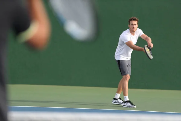 Tennis serve player man serving ball during match point on outdoor green court. Two men athlete playing sport game training doing exercise — ストック写真