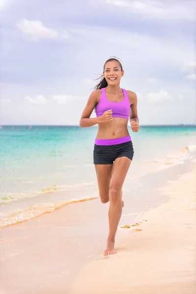Correr mujer trotar en la playa en las vacaciones de viaje del Caribe que viven un estilo de vida saludable en sujetador deportivo ropa deportiva y pantalones cortos con piernas en forma. Feliz joven asiática chica —  Fotos de Stock