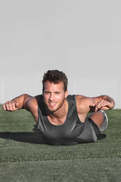 Övningar i nedre delen av ryggen för att stärka musklerna för ryggradshälsa. Fitness man gör Stålmannen träning träning med armarna upp på gymmet golvet. Kroppsviktsträning. — Stockfoto