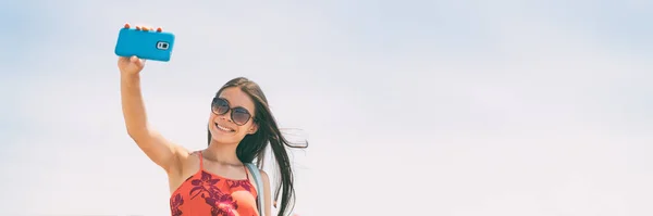 Foto selfie con la mujer del teléfono turista sosteniendo teléfono celular tomando foto autorretrato en las vacaciones de verano. Panorama de estilo de vida de los jóvenes con espacio de copia sobre fondo azul cielo —  Fotos de Stock