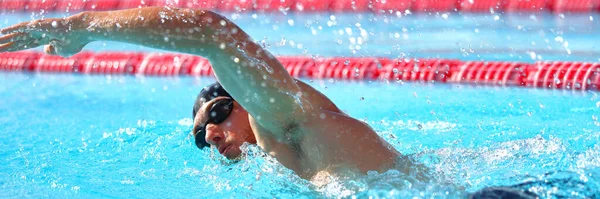 Swimmer man athlete swimming in pool lanes doing a lap. Swim race in crawl. Banner panorama crop — стоковое фото