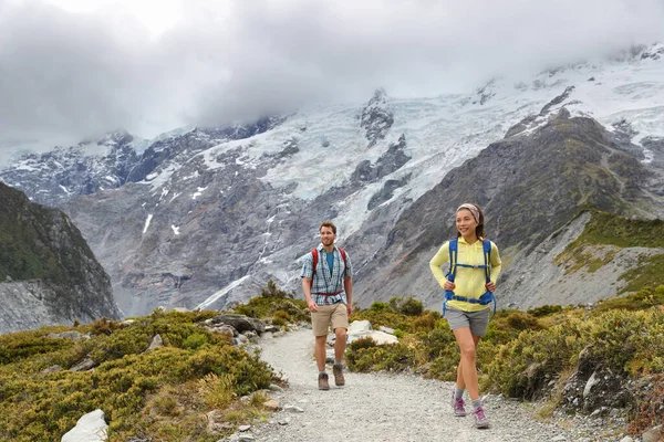 Nieuw-Zeelandse backpackers tramping op Mount Cook Aoraki Hooker vallei reizen. Backpackers wandelen op het Hooker Valley Track. Sneeuw bedekte bergen gletsjer landschap. Paar op avontuur Stockfoto