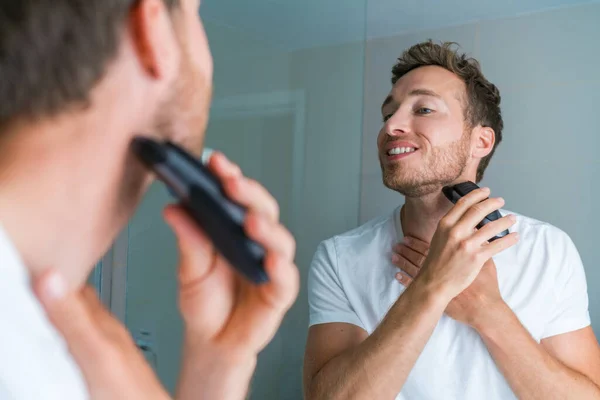 Young man shaving neck and jawline in the morning using electric shaver clipper. Morning routine modern lifestyle. Male beauty 30s model — стоковое фото