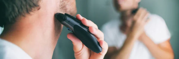 Man shaving beard using electric trimmer shaver. Male beauty grooming banner panorama. Home lifestyle young person looking at bathroom mirror trimming hair on neck — Stock Photo, Image