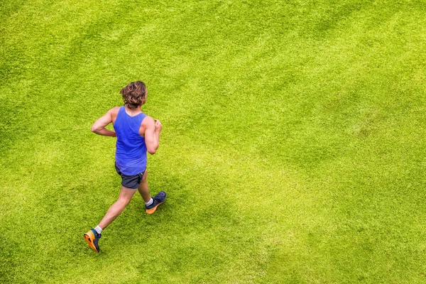 Runner man running jogging on grass — стоковое фото