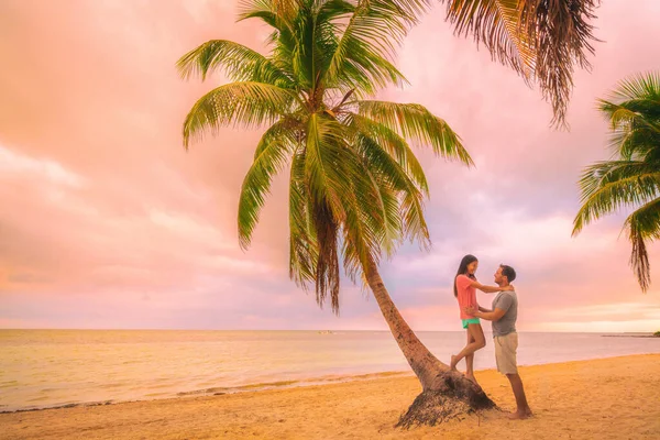 Romantisk solnedgång promenera unga par i kärlek omfamna på palmer vid rosa skymning moln himmel. Romans på sommaren resa semester — Stockfoto