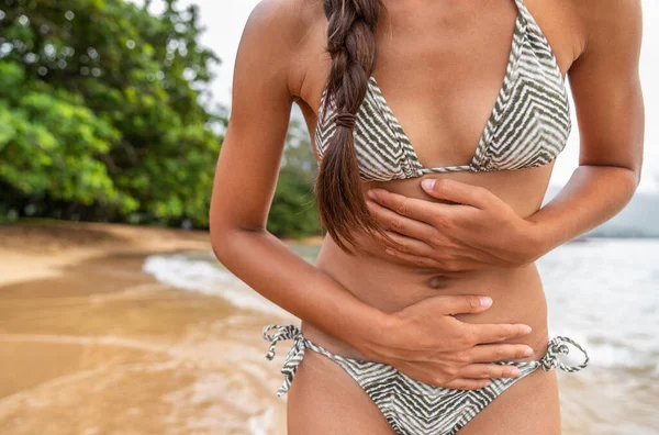 Estómago enfermedad de viaje mujer turista con calambres dolorosos en la playa tropical - concepto de gastroenteritis por norovirus. Calambre dolor seguro de salud —  Fotos de Stock