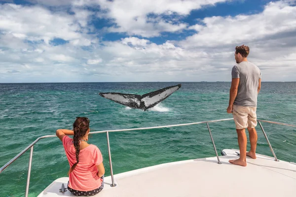 Observação de baleias turismo de barco turistas pessoas em navio olhando para a cauda jubarte rompendo o oceano em destino tropical, férias de viagem de verão. Casal no convés de catamarã Fotografia De Stock