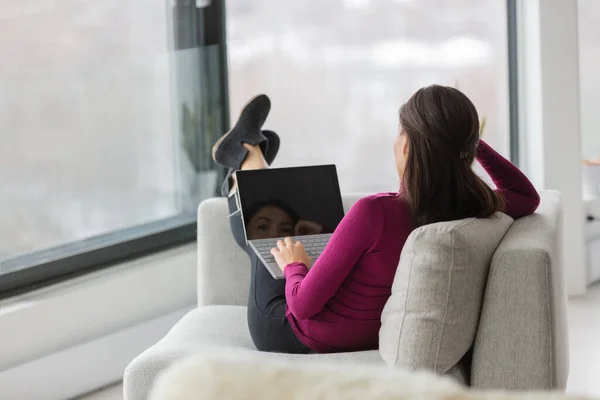 Online klas student thuis studeren kijken videocall werken op laptop ontspannen in de bank van de woonkamer. Meisje voeten omhoog ontspannen in appartement terloops kijken naar zwart scherm van de computer — Stockfoto