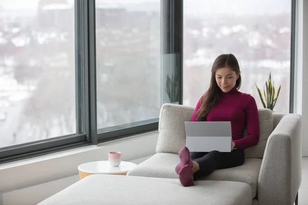 Werken vanuit huis Aziatische vrouw op afstand werken met behulp van laptop gelukkig ontspannen zitten op de bank in de woonkamer tijdens coronavirus lockdown — Stockfoto