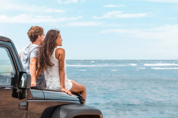 Viaje en coche viaje en carretera pareja turistas disfrutando de vista al mar relajarse en la capucha del coche utilitario deportivo. Feliz mujer asiática, hombre amigos sonriendo en la playa. —  Fotos de Stock
