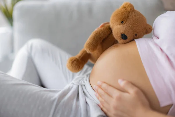Zwangere vrouw strelen buik knuffelen teddy beer baby speelgoed op zwangerschap hobbel wachten voor de geboorte van haar kind — Stockfoto