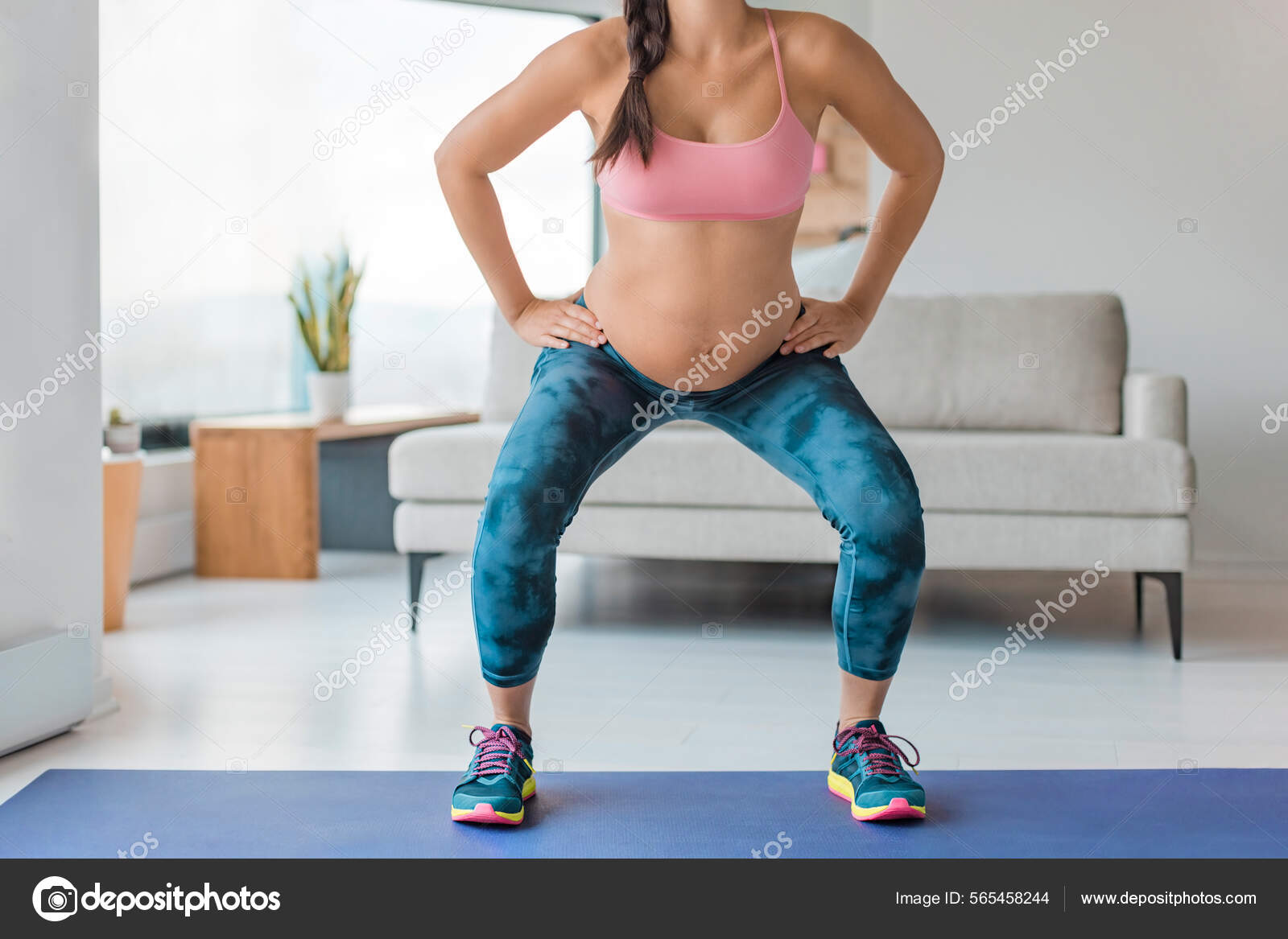 Home workout pregnant woman squatting doing leg workout squat with fitness  online class standing on yoga mat. Pregnancy prenatal exercise Stock Photo  by ©Maridav 565458244