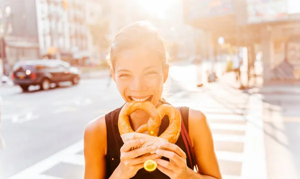 Γυναίκα τρώει πρέτσελ στο Μανχάταν, ένα κλασικό σνακ της Νέας Υόρκης. Πολυφυλετική ασιατική νεαρή επαγγελματική πορτρέτο χαμογελώντας στην κάμερα — Φωτογραφία Αρχείου
