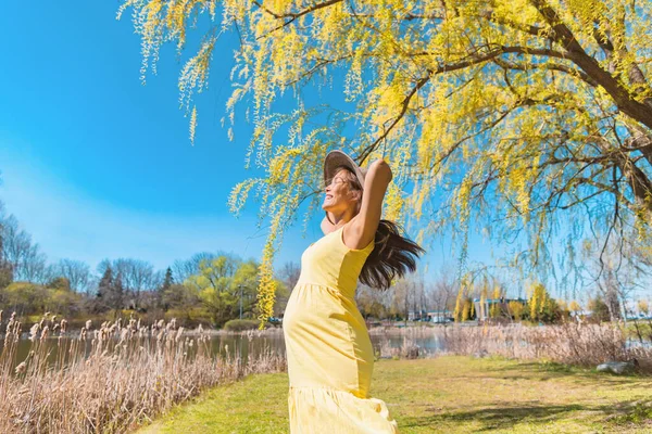快乐的亚洲孕妇穿着太阳帽和黄色衣服在大自然的公园里自由自在地跳舞 怀孕快乐和无忧无虑 — 图库照片