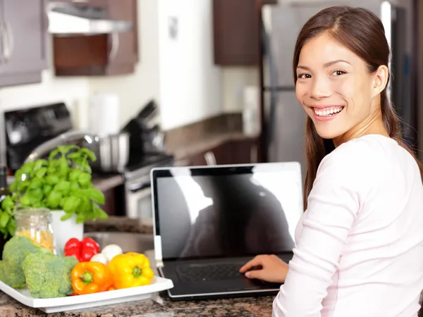 Mulher usando computador portátil na cozinha — Fotografia de Stock