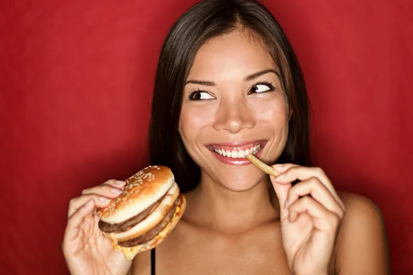Женщина с фаст-фудом ест бургер — стоковое фото