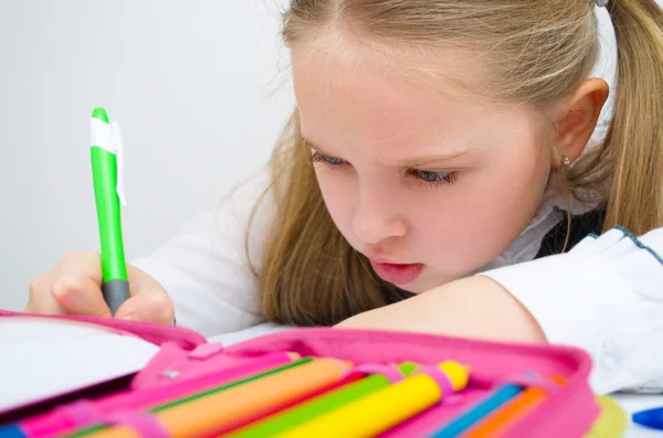 Pequena estudante escrevendo lição de casa — Fotografia de Stock