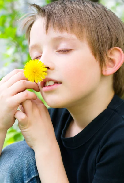Мальчик нюхает желтый цветок — стоковое фото