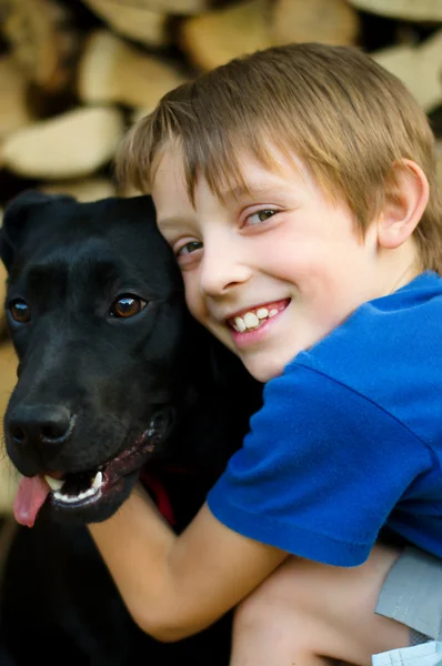 Хлопчик обіймає чорного собаку — стокове фото