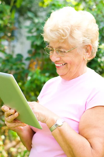 Mujer mayor que trabaja en una tableta — Foto de Stock
