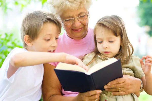 Mormor läser en bok för barnbarn Royaltyfria Stockbilder