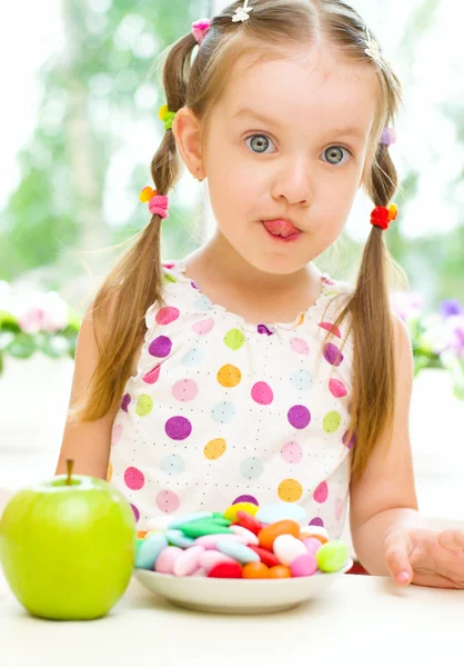 Child choosing between apple and sweets — Stock Photo, Image