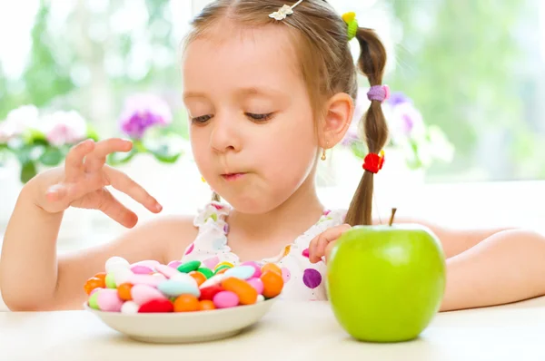 Niño eligiendo entre manzana y dulces — Foto de Stock
